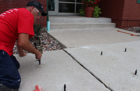 A concrete technician is applying the chemical compound to a residential slab.