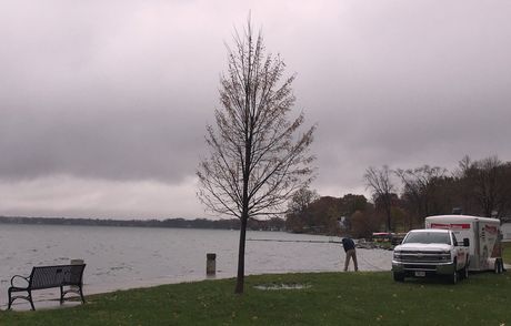 A white van is parked on the shore of a lake