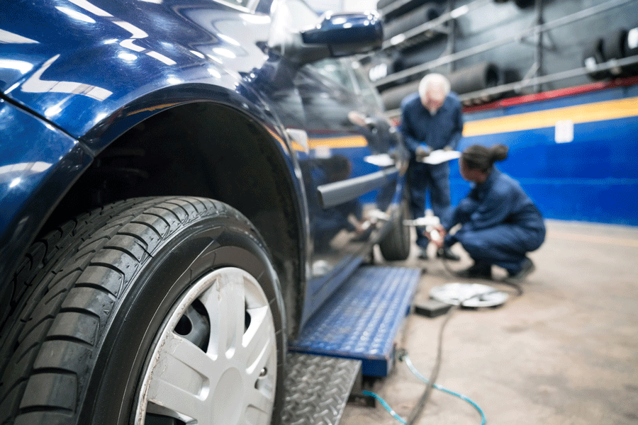 A Man and A Woman Are Working on A Car in A Garage.