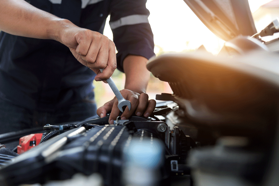 A Man Is Working on The Engine of A Car with A Wrench.