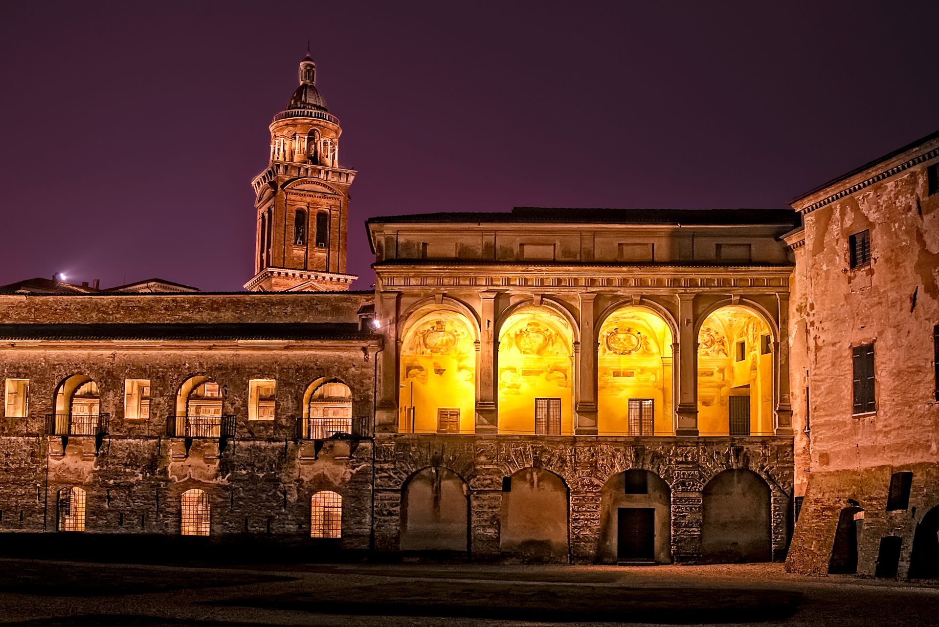 A large building with arches and a clock tower at night