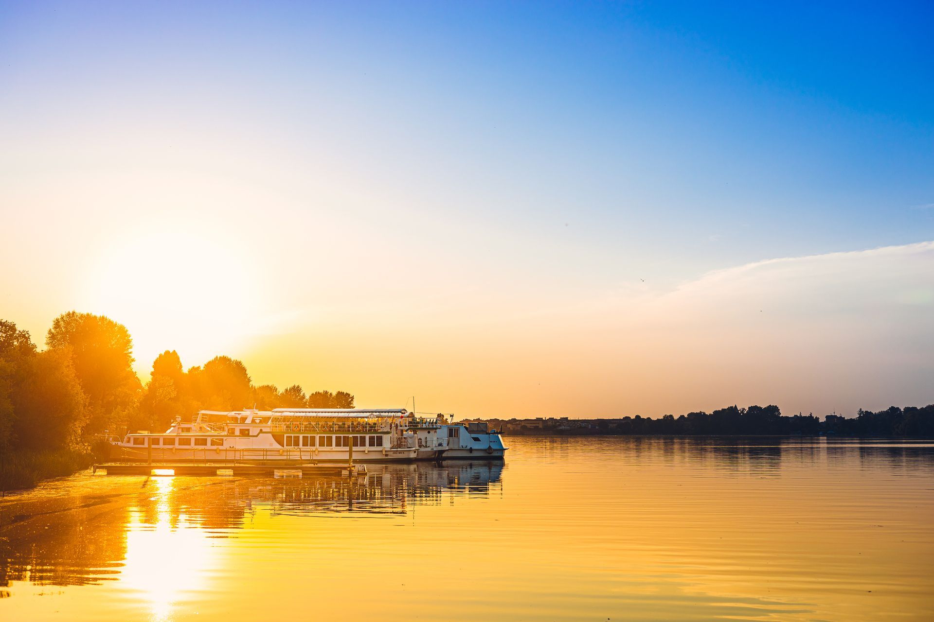 A boat floats on a river at sunset.