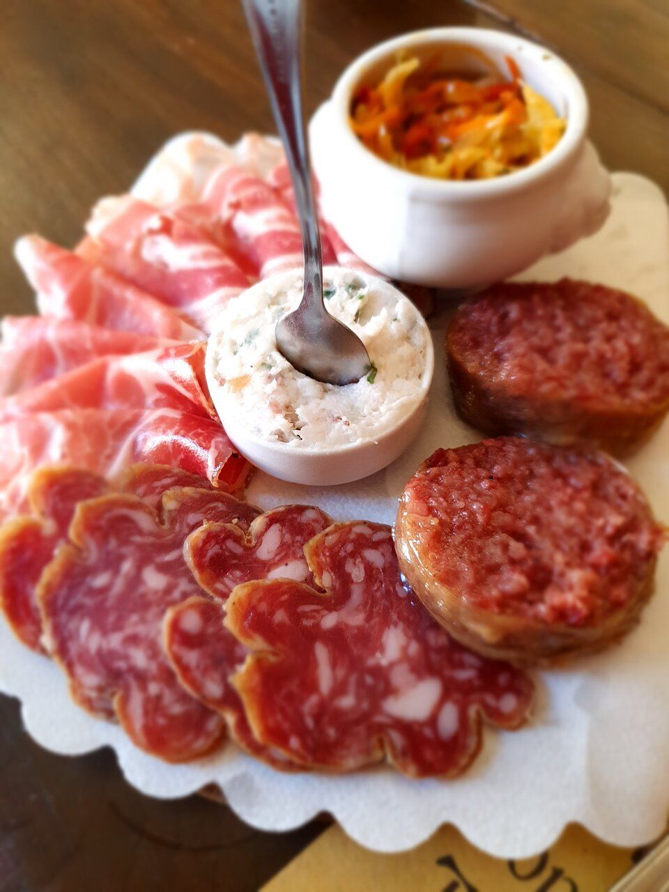 A plate of meat with a bowl of sauce and a spoon