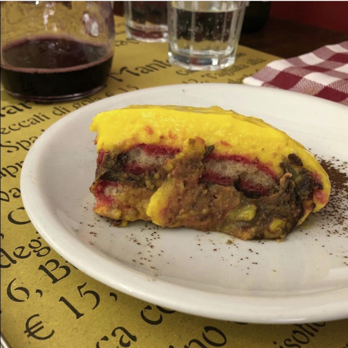 A white plate with a piece of food on it and a glass of wine in the background