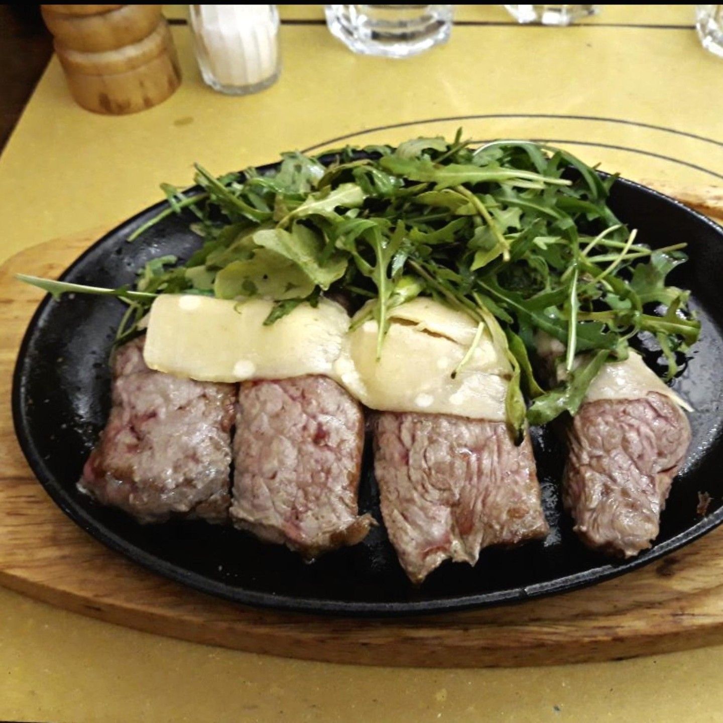 A plate of meat with cheese and vegetables on a table