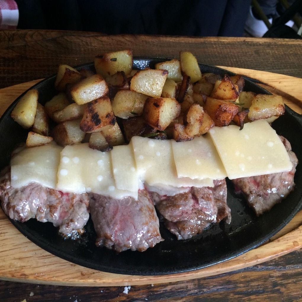 A plate of food with meat and potatoes on a wooden table
