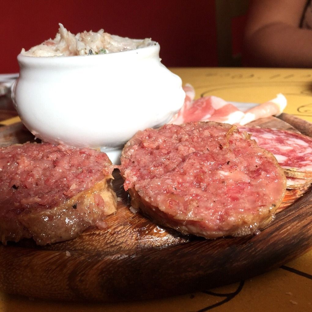 Un tagliere di legno condito con carne e una ciotola di zuppa