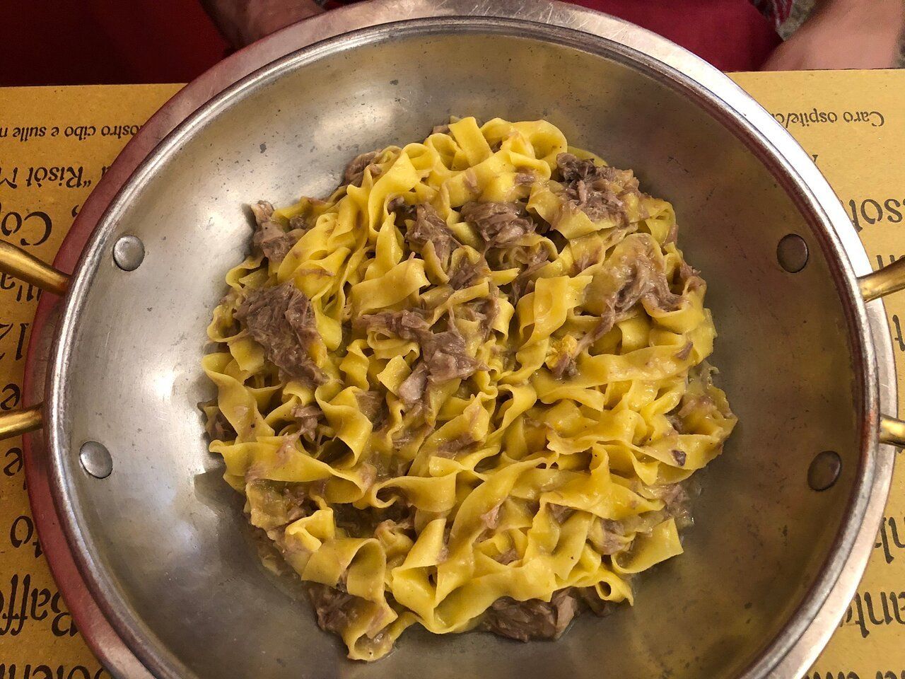 Una padella piena di tagliatelle e carne su un tavolo