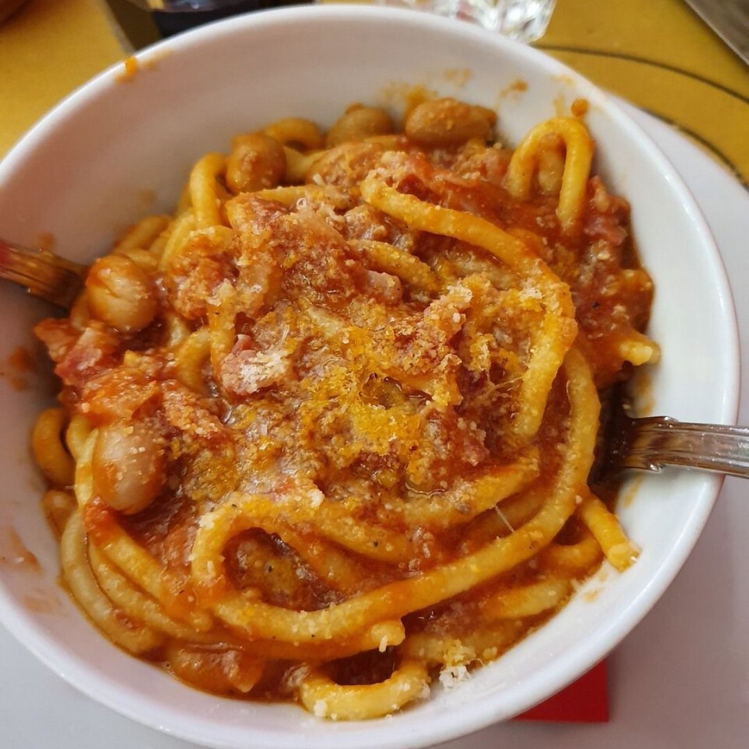 Una ciotola bianca piena di tagliatelle e salsa con una forchetta