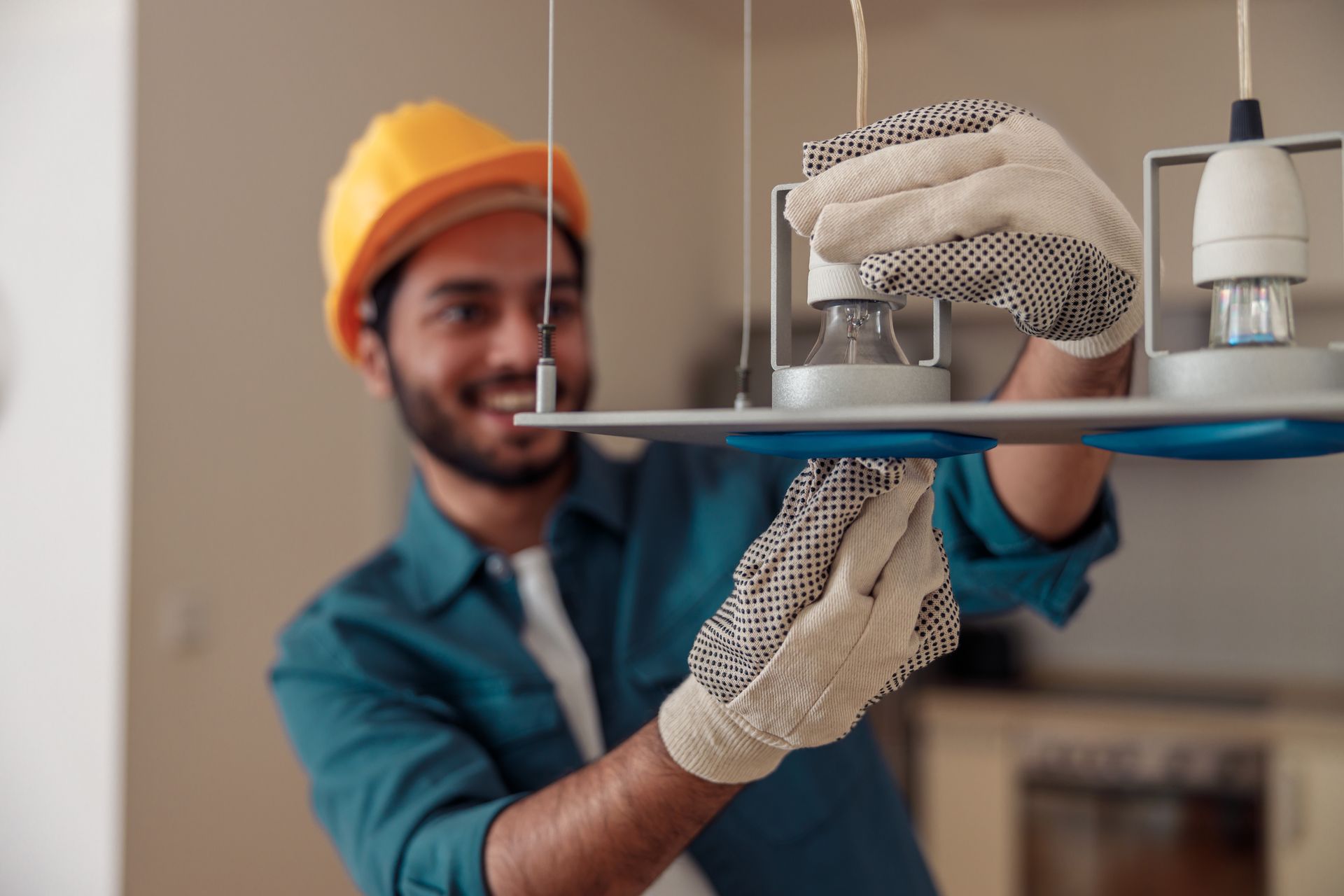 Worker in orange hard hat loading a box onto a shelf with gloved hands.