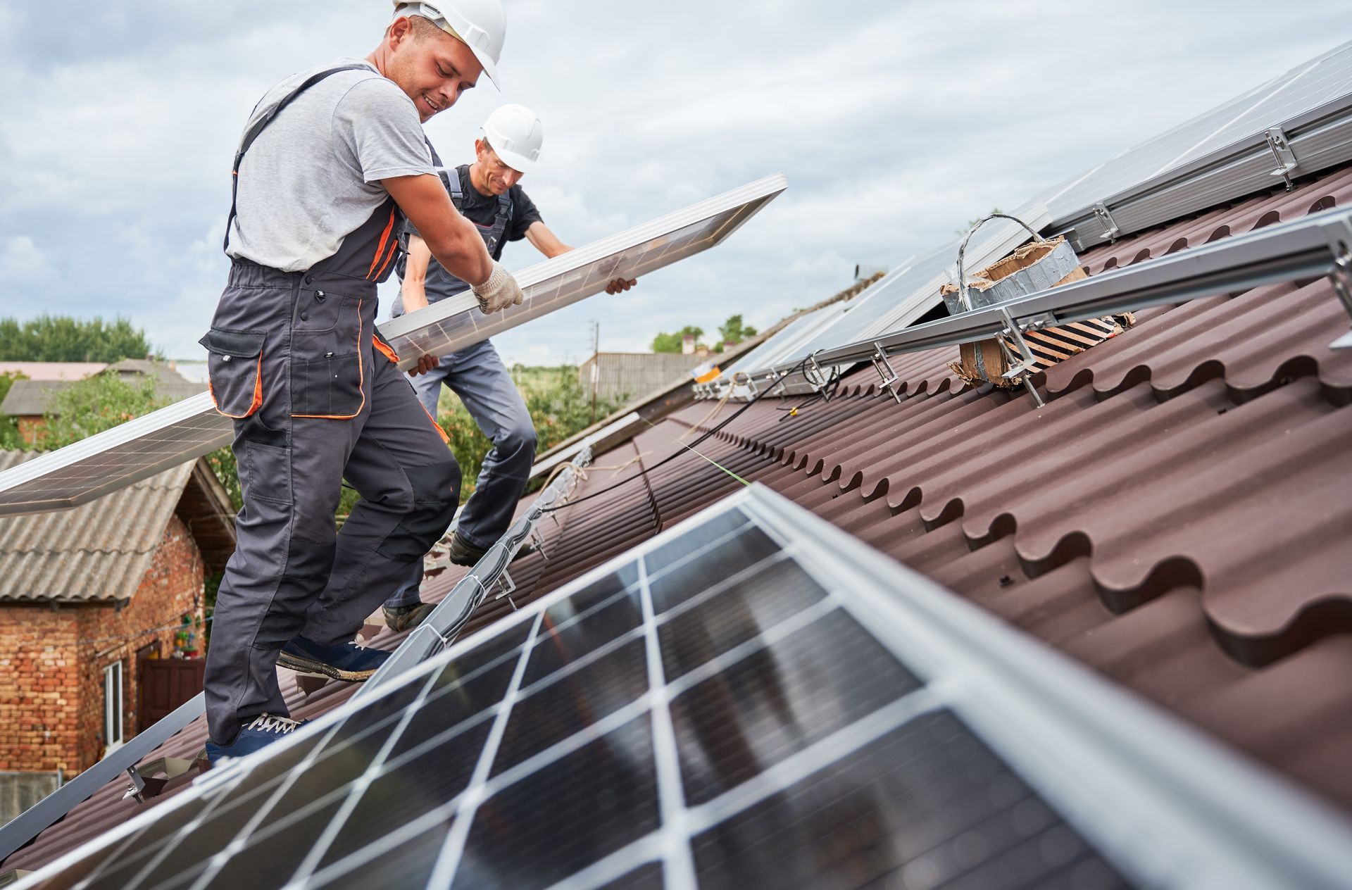 Two men are installing solar panels on the roof of a house.