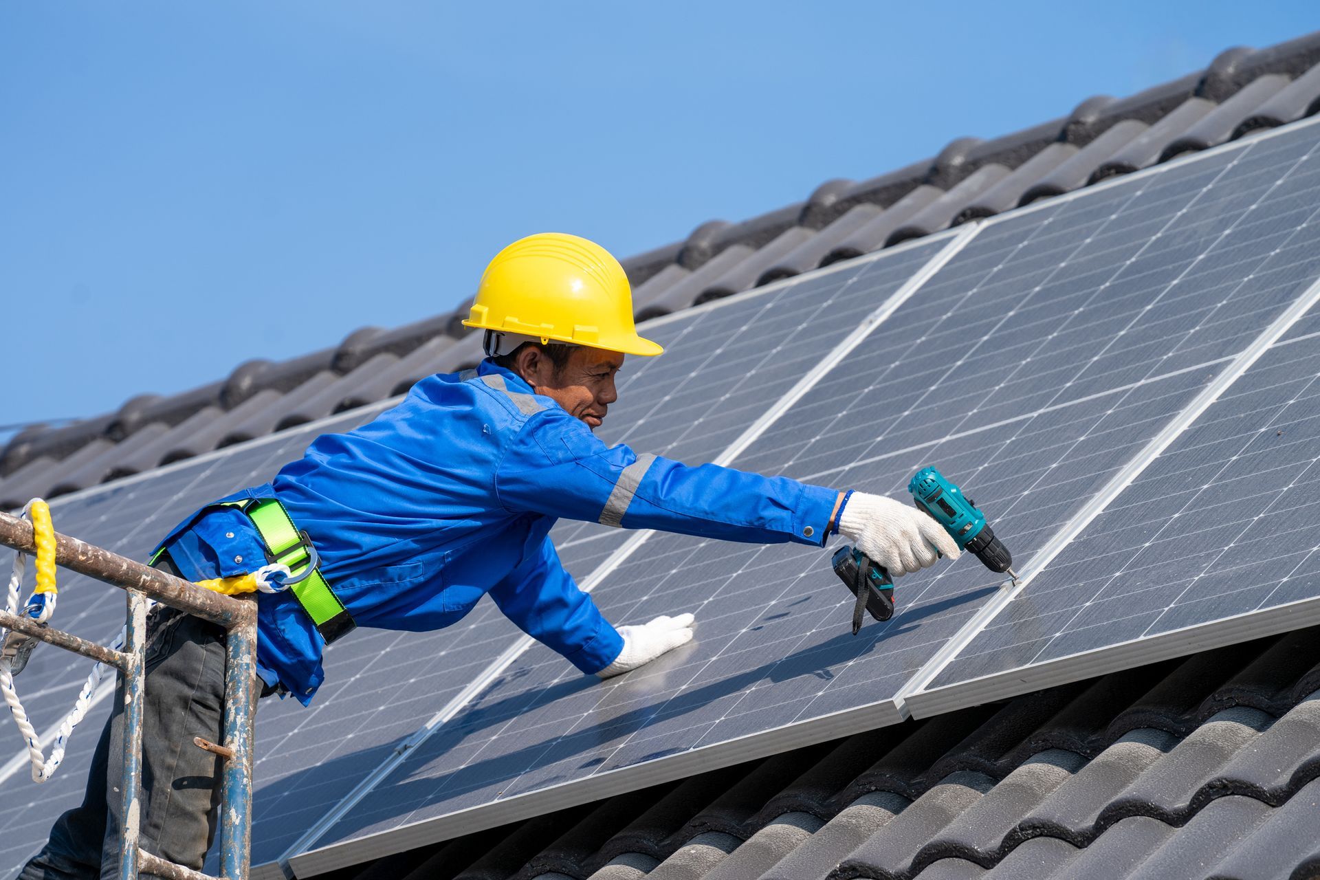 A man is installing solar panels on the roof of a house.