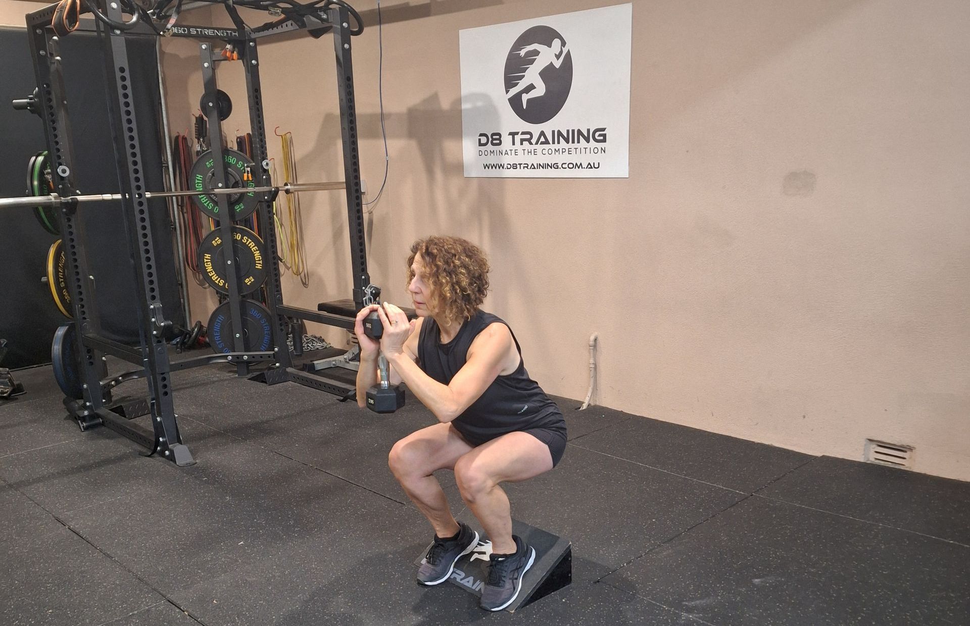 Person doing a squat hold with a cable machine in a gym.