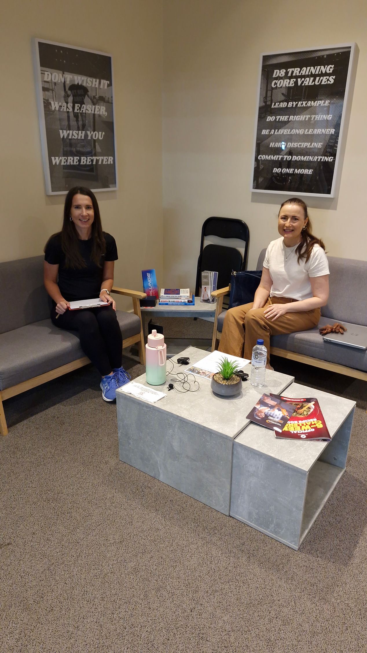 Two women are sitting in a waiting room talking to each other.