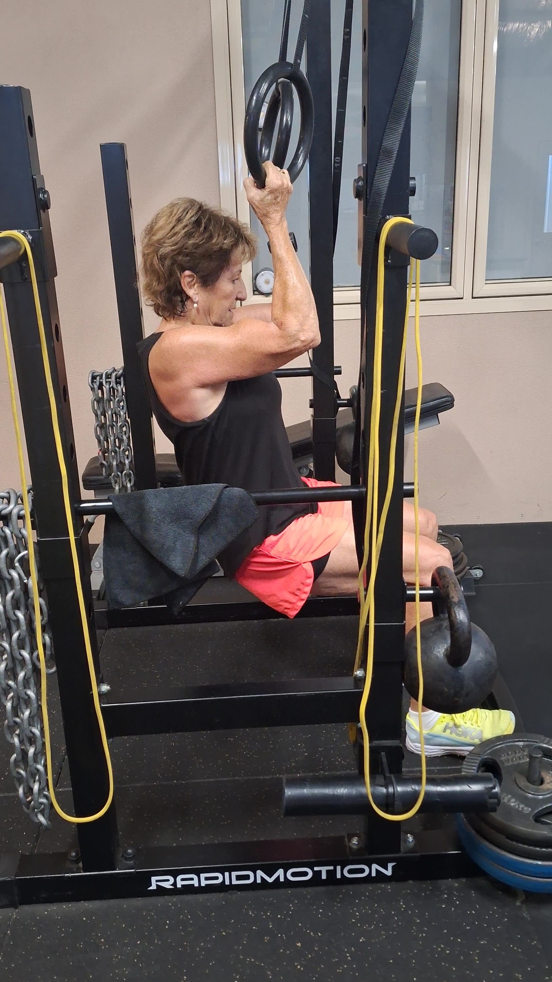 Three people doing dumbbell wall sits against a tan wall, indoors.