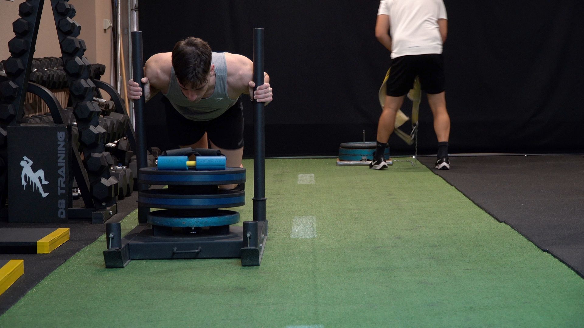 Three people doing dumbbell wall sits against a tan wall, indoors.