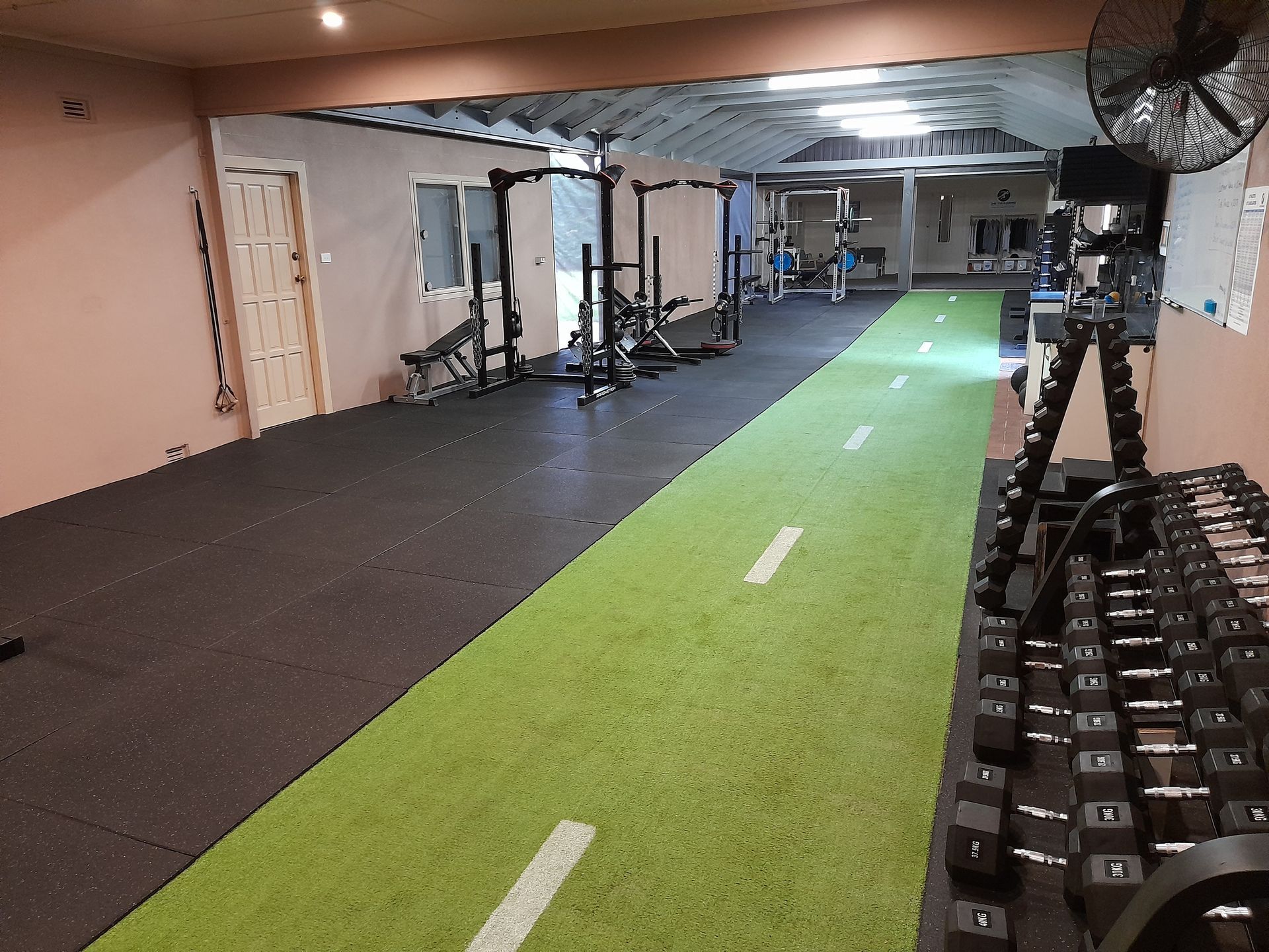 Indoor gym with turf running lane, weight racks, and exercise equipment along the walls.
