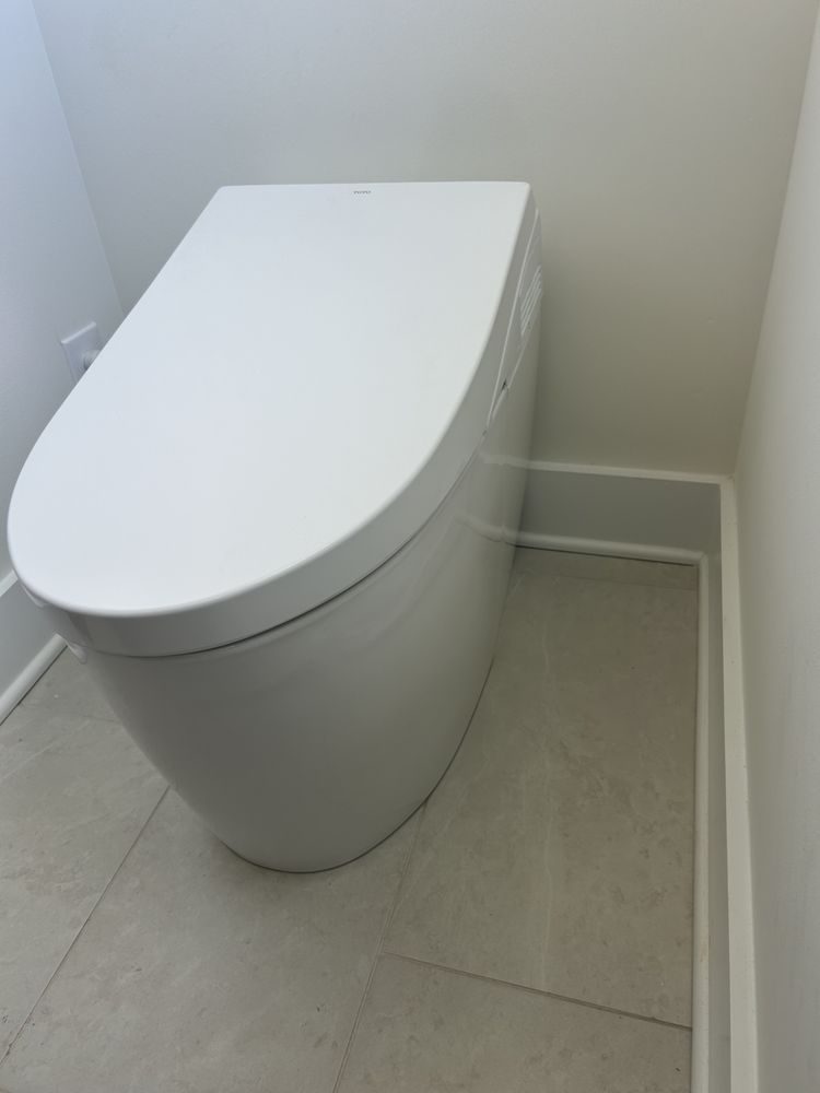 Modern white toilet in a small tiled bathroom corner