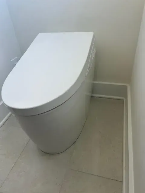White modern toilet in a small tiled bathroom corner.
