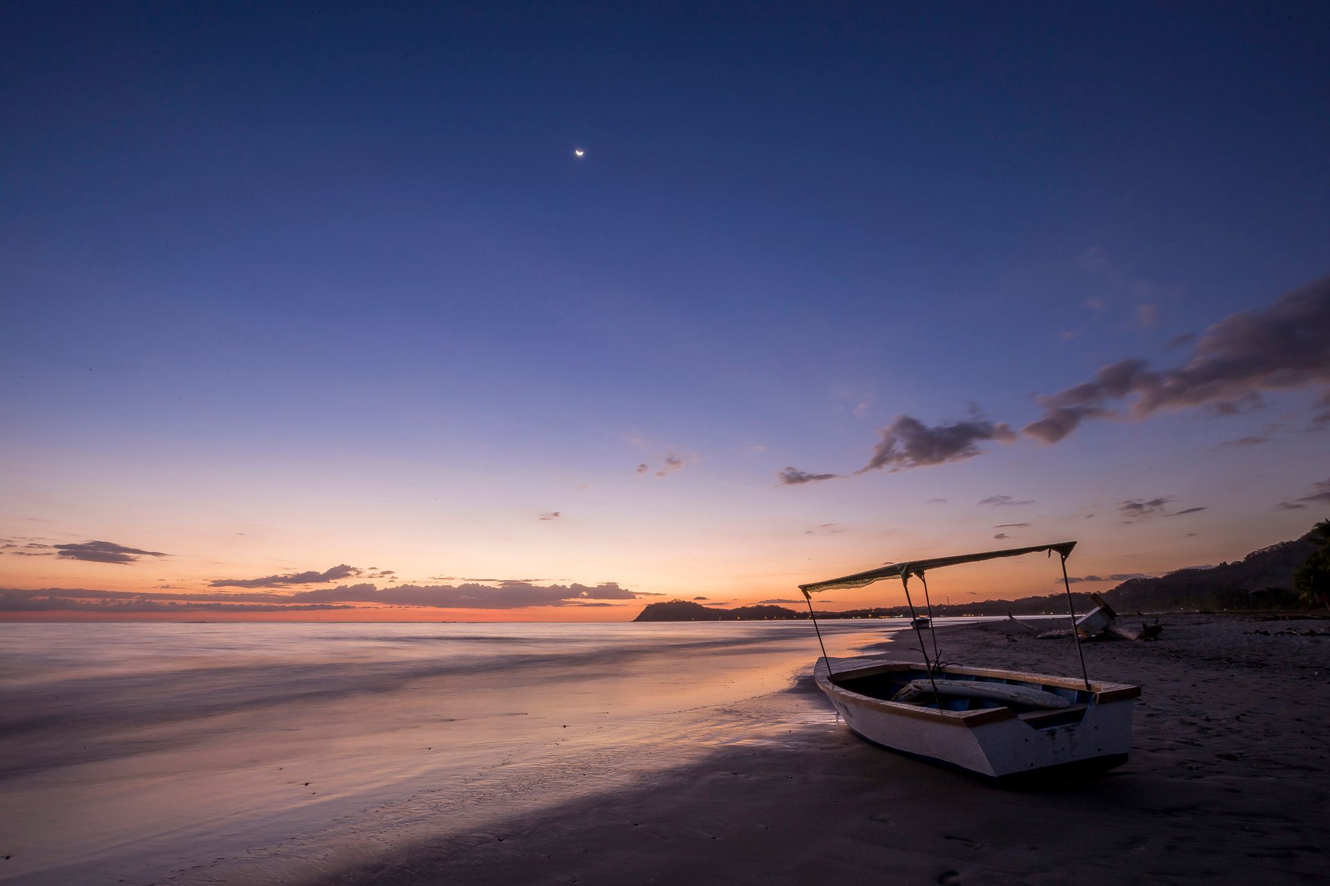 Boat on a beach at dusk, under a blue sky with a bright star.