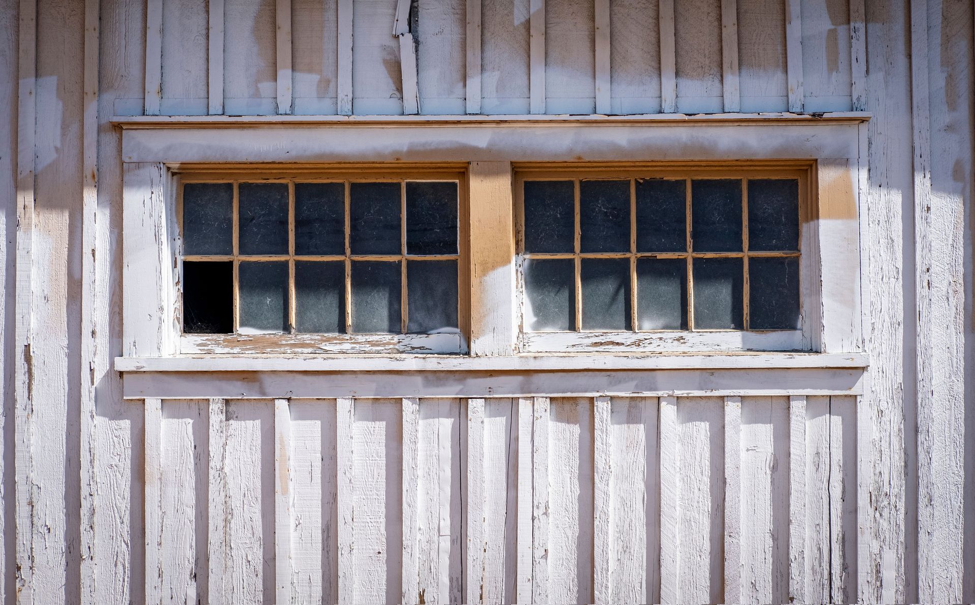 Weathered white barn wall with two small multi-pane windows