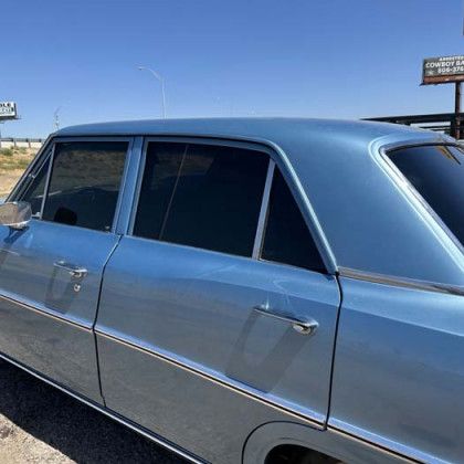 Light blue classic car parked outside on a sunny day.