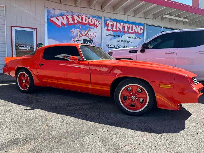 Bright orange classic car parked in front of a window tinting business.