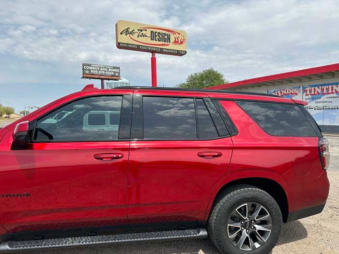 Red SUV with tinted windows parked in front of a business with signage.