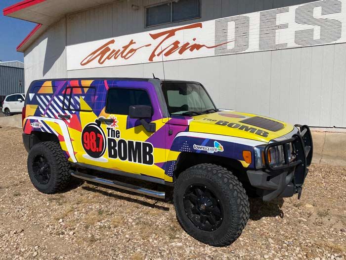 A colorful Hummer H3 with custom wrap advertising 