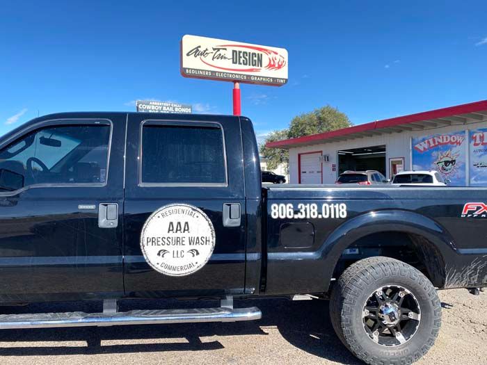 Black pickup truck with AAA Pressure Wash LLC logo and Auto Tint Design sign.