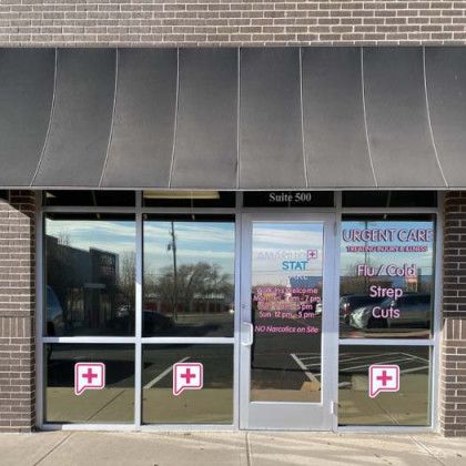 Urgent care clinic with a black awning and window decals advertising services.