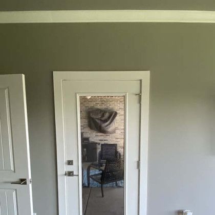 Doorway reflecting a room with brick wall, chair, and furniture. Grey walls.