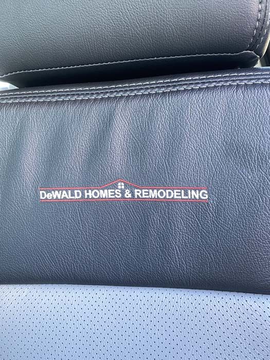 Black leather with DeWald Homes & Remodeling logo in white and red.
