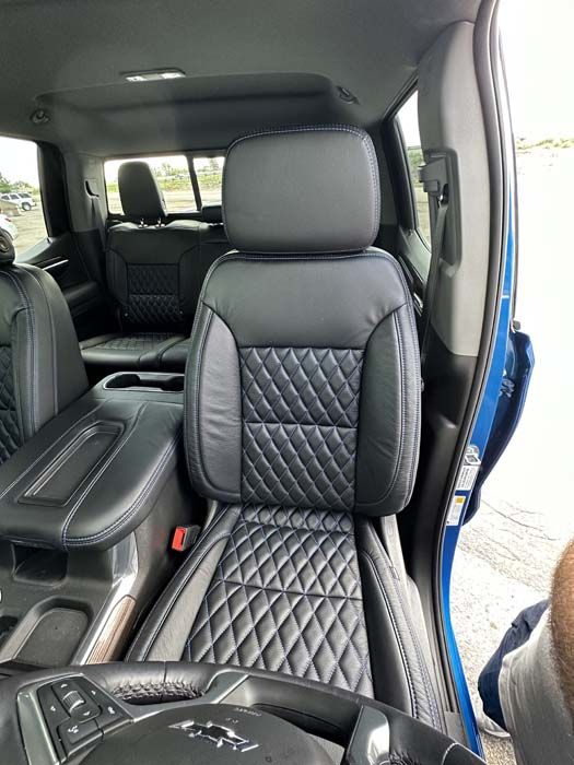 Black diamond-stitched leather car seats in a blue vehicle.