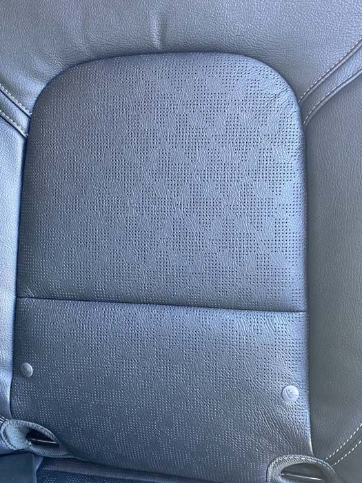 Black perforated car seat with a rounded top and two visible rivets.