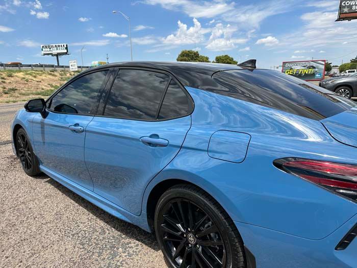 Blue Toyota Camry with black roof and tinted windows, parked on a sunny day.