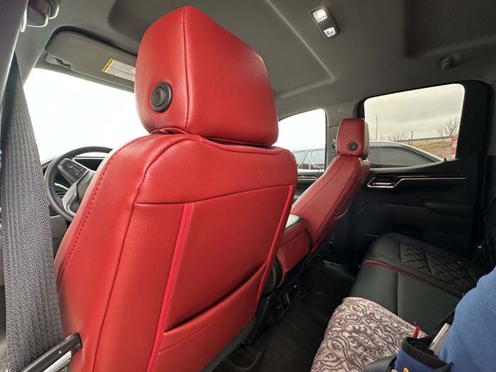 Red leather interior of a vehicle, seats visible. Back seats are black. Passengers are present.