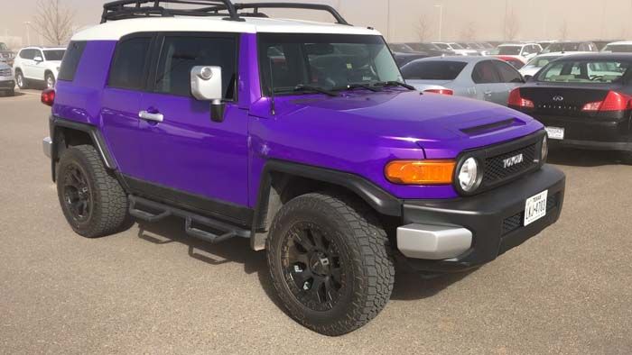 Purple Toyota FJ Cruiser with a white roof, parked in a lot.