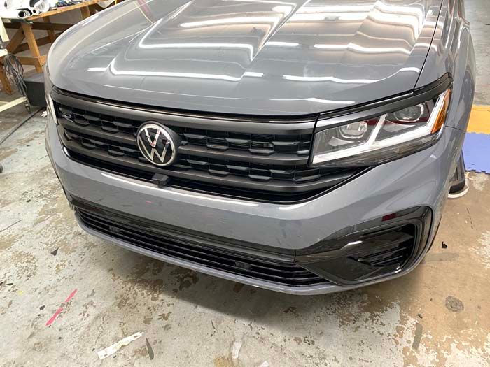 Gray Volkswagen Atlas front view, black grille, shiny exterior, indoors.