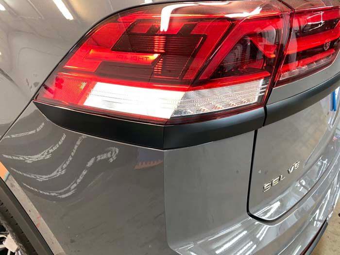 Gray car's rear corner with a red and white taillight. 