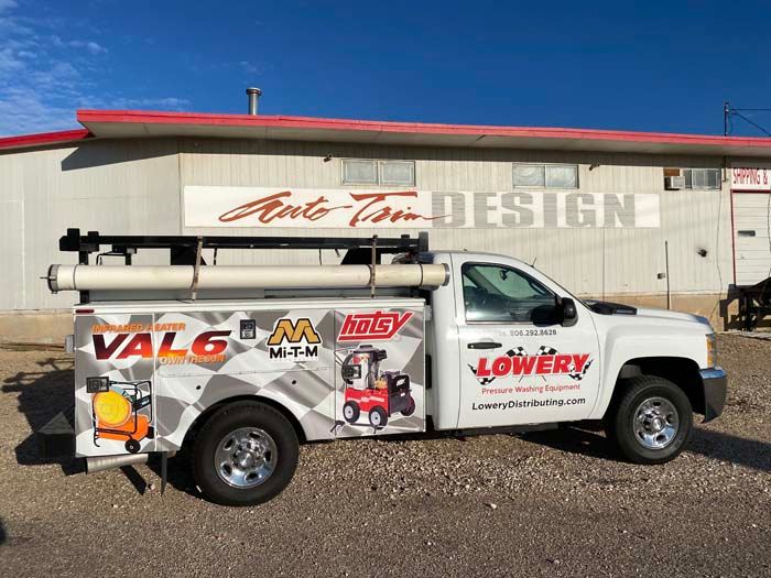 White work truck with company logos parked in front of a building.