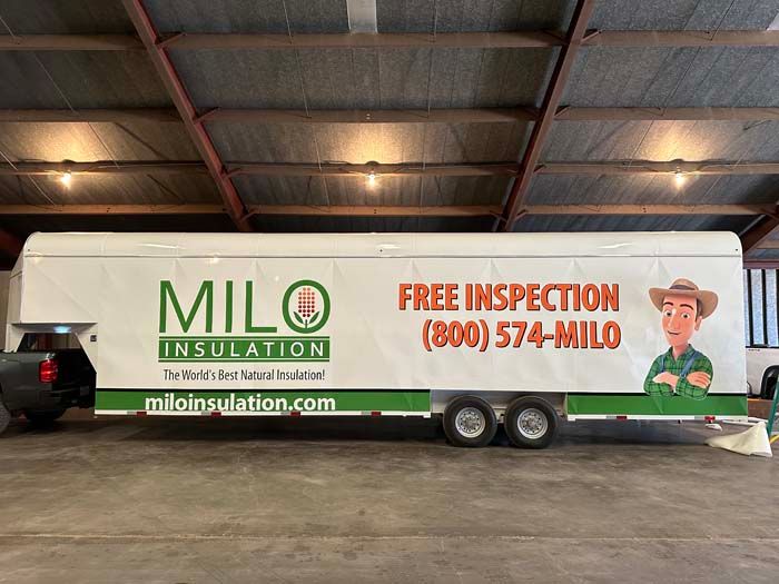 Milo Insulation trailer with logo and contact info in a warehouse.