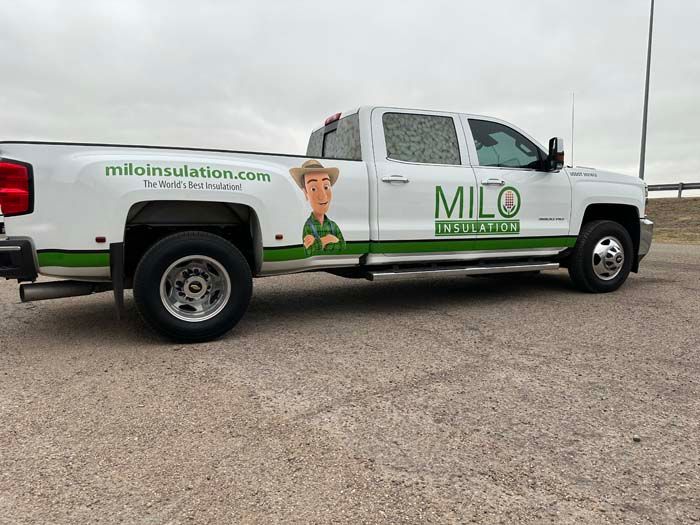 White Milo Insulation truck with green accents and cartoon logo parked outdoors.
