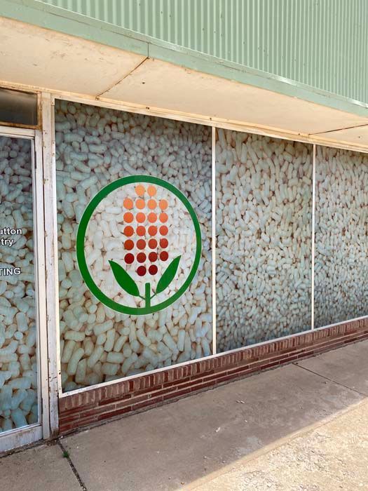 Building with a green and red logo on the window. Background shows many white pill-like shapes.