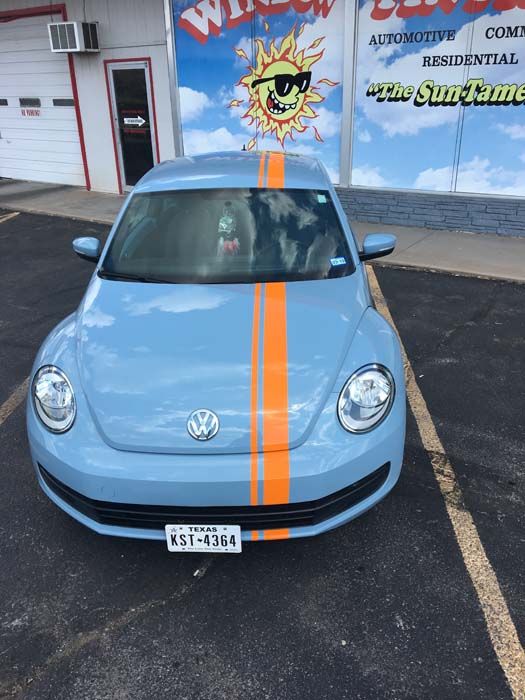 Blue VW Beetle with orange racing stripes in front of a window tinting shop.