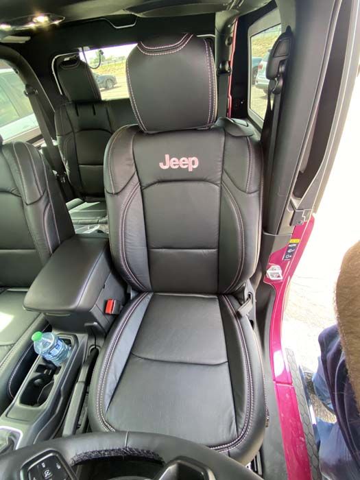 Black leather Jeep seat with red stitching and Jeep logo. Interior shot.