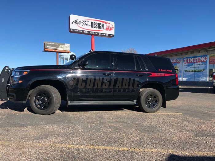 Black Constable SUV parked in front of a shop with a blue sky background.