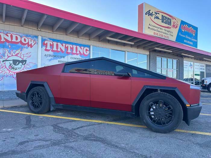 Red matte Cybertruck parked outside a window tinting business.