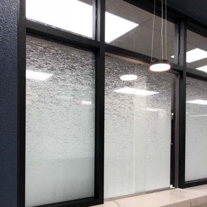 Black-framed windows with textured, frosted glass; a modern interior, blue wall, and a hanging light.