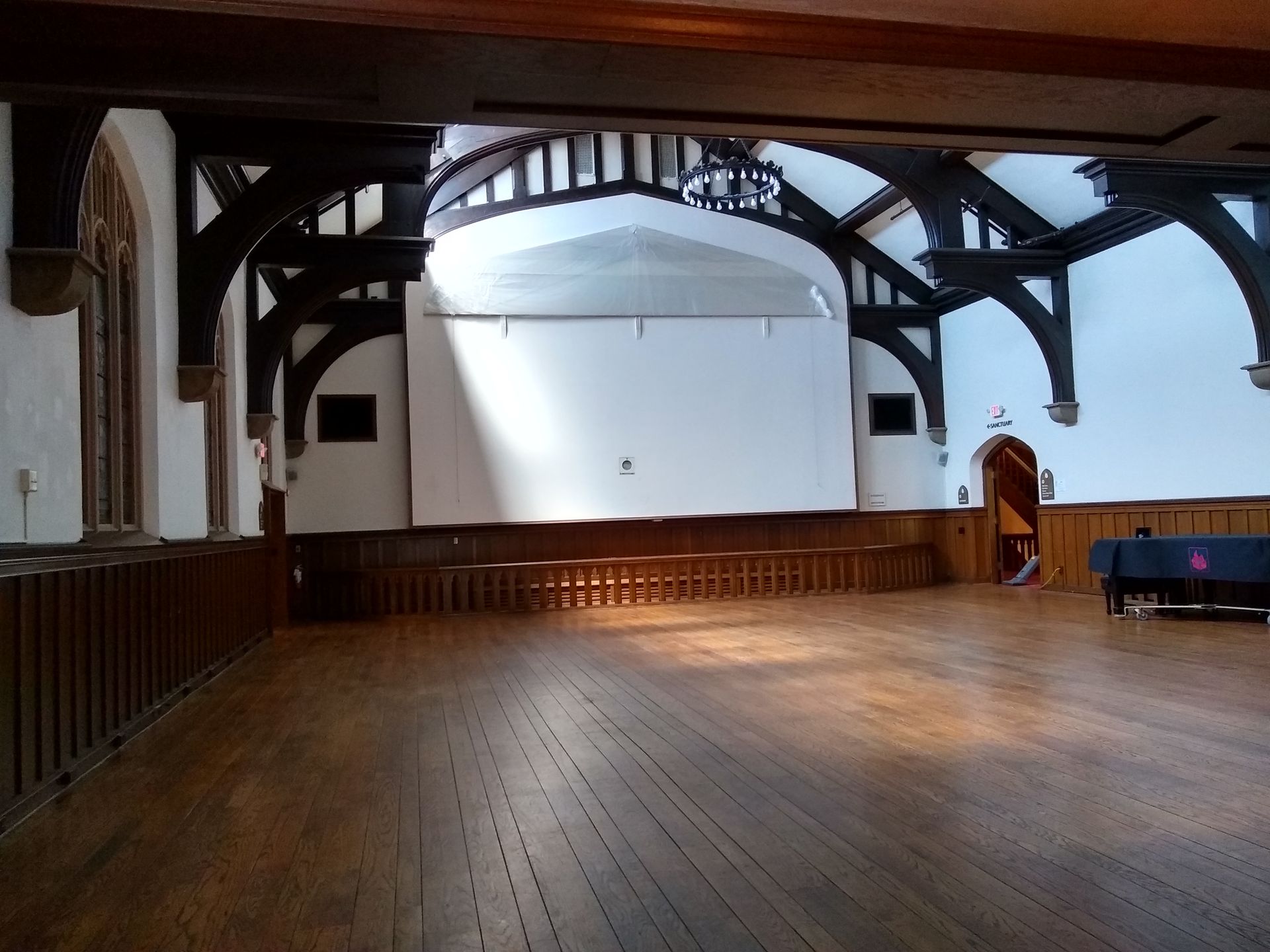 Empty wooden hall with a stage, arched beams, and a lectern at the front.